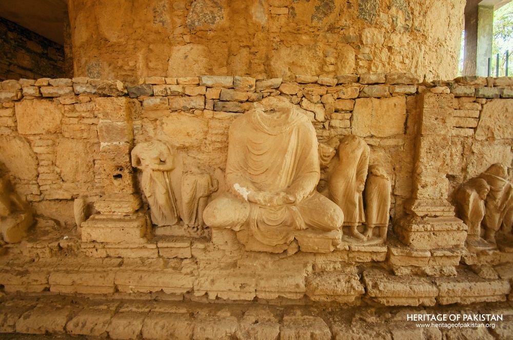 Central seated figure with attendants carved in stone relief.